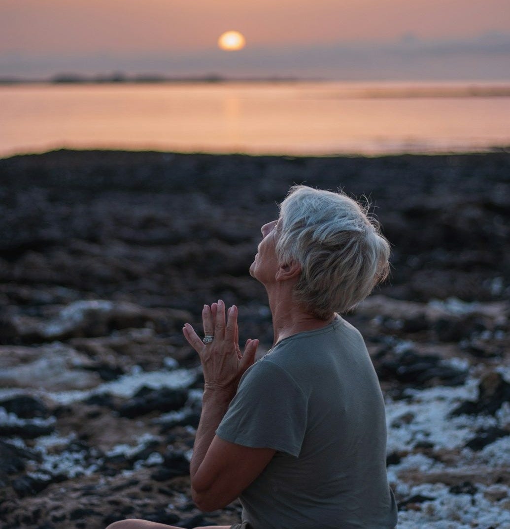 a woman sitting on a rock in front of a body of water a woman sitting on a rock in front of a body of water