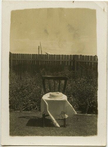 This may contain: an old photo of a table and chair in the yard
