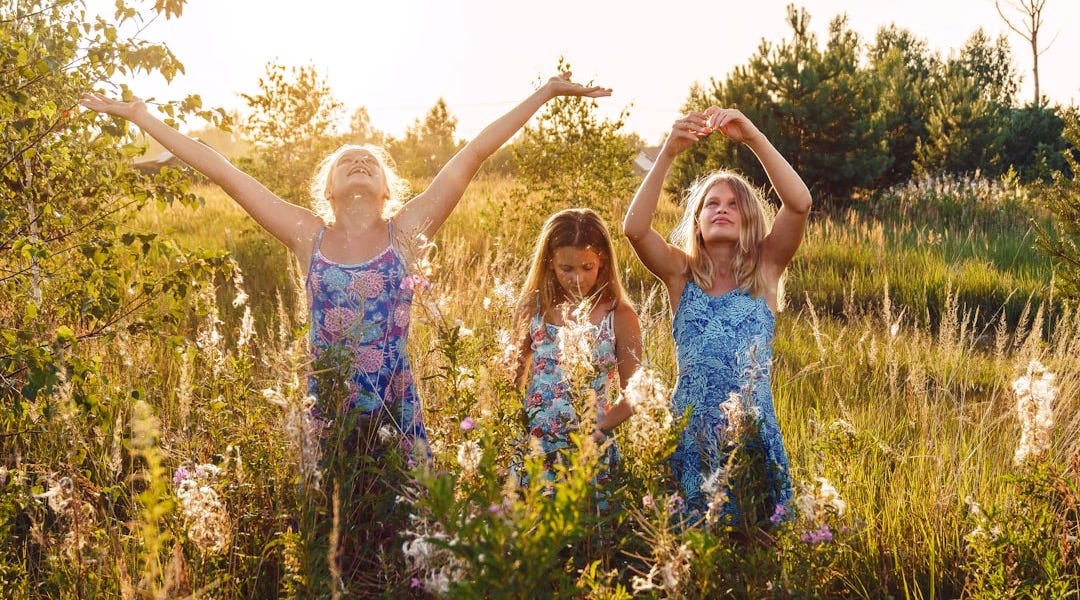 2 women in blue and white floral dress standing on green grass field during daytime