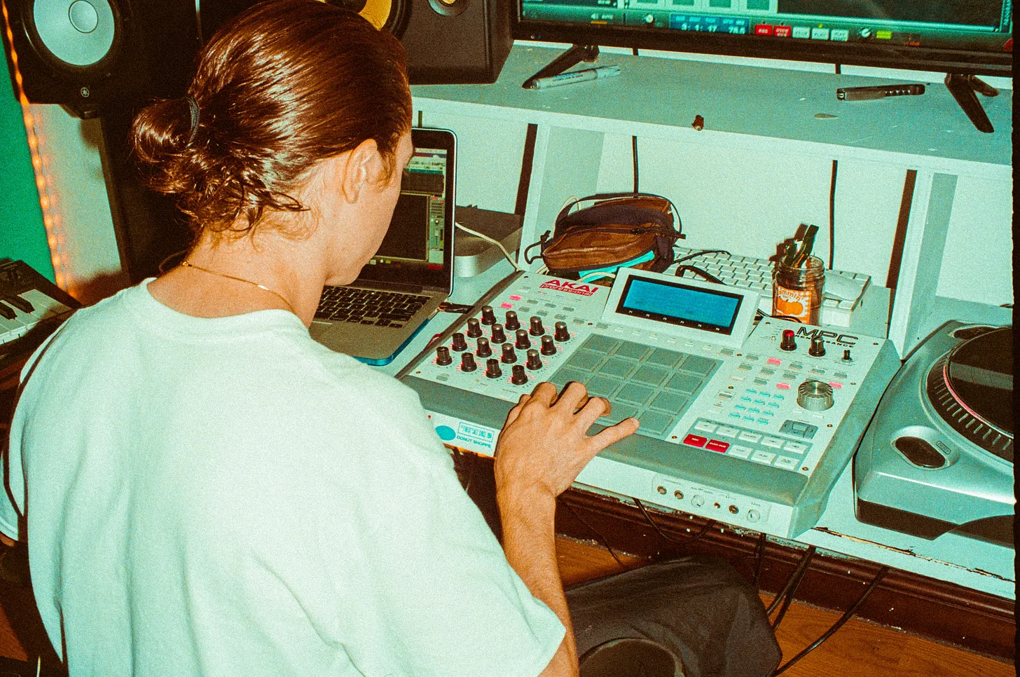 a picture of a man playing with a retro 90s synth in a studio
