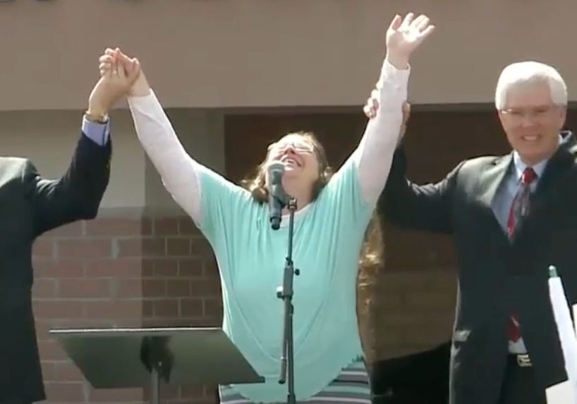 former kentucky county clerk kim davis upon leaving jail, holds the hands of her lawyers up in the air with her head tilted back like she's about to start speaking in tongues former kentucky county clerk kim davis upon leaving jail, holds the hands of her lawyers up in the air with her head tilted back like she's about to start speaking in tongues