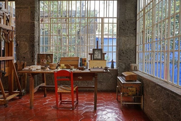 This may contain: a room filled with lots of windows next to a table and chair in front of a window