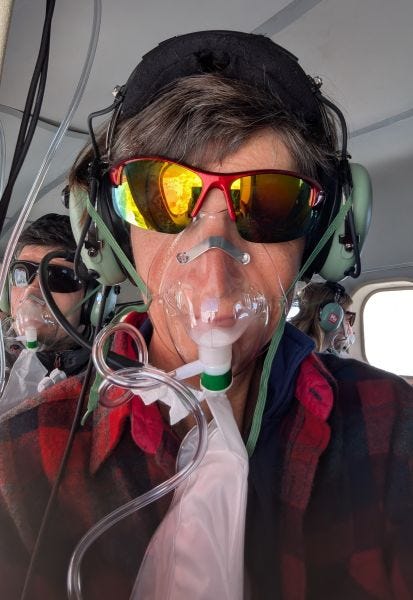 me in a red plaid flannel shirt and mirrored wrap-around sunglasses, also wearing headphones and an oxygen mask