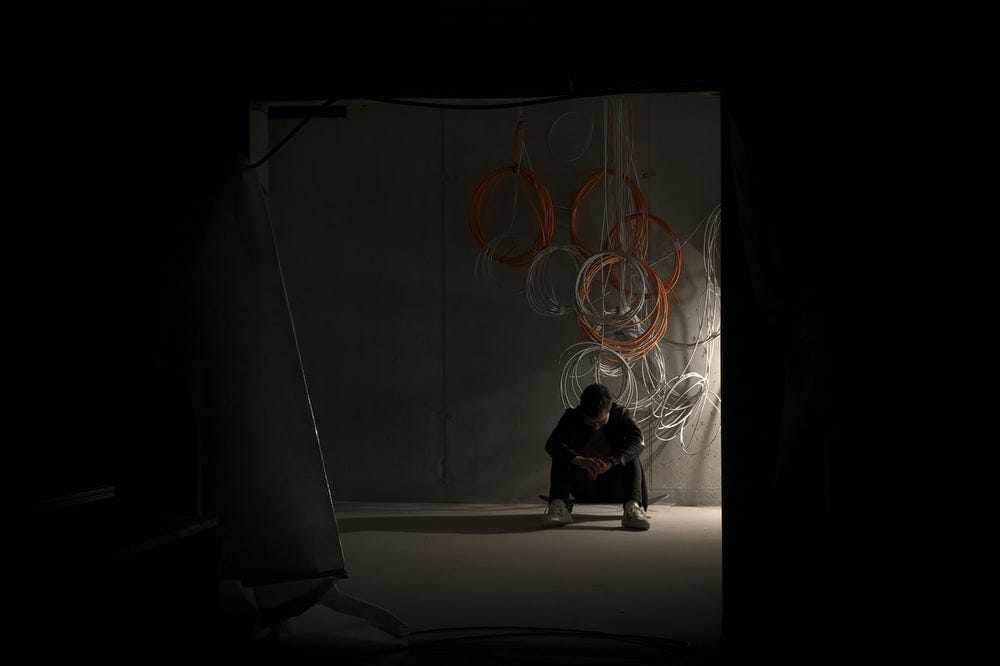 man sitting on his skateboard in a dark room