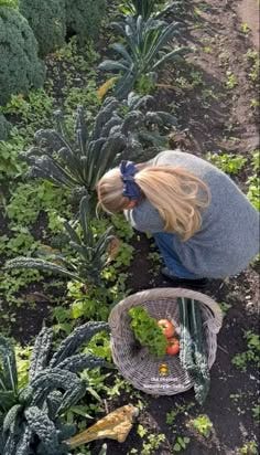 This may contain: a woman kneeling down in the middle of a garden with lots of plants and vegetables