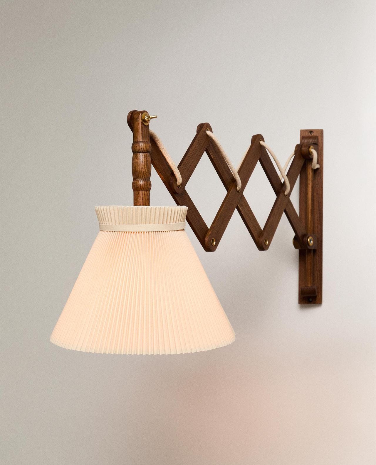 Brown wall light with concertina-style extendable arm and pleated white conical shade. Brown wall light with concertina-style extendable arm and pleated white conical shade.