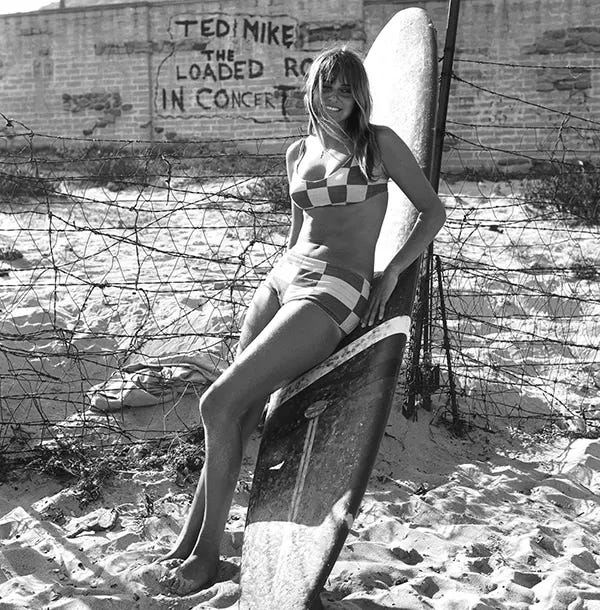 A woman in a checkered bikini leaning on her surfboard in Los Angeles, circa 1967. A woman in a checkered bikini leaning on her surfboard in Los Angeles, circa 1967.