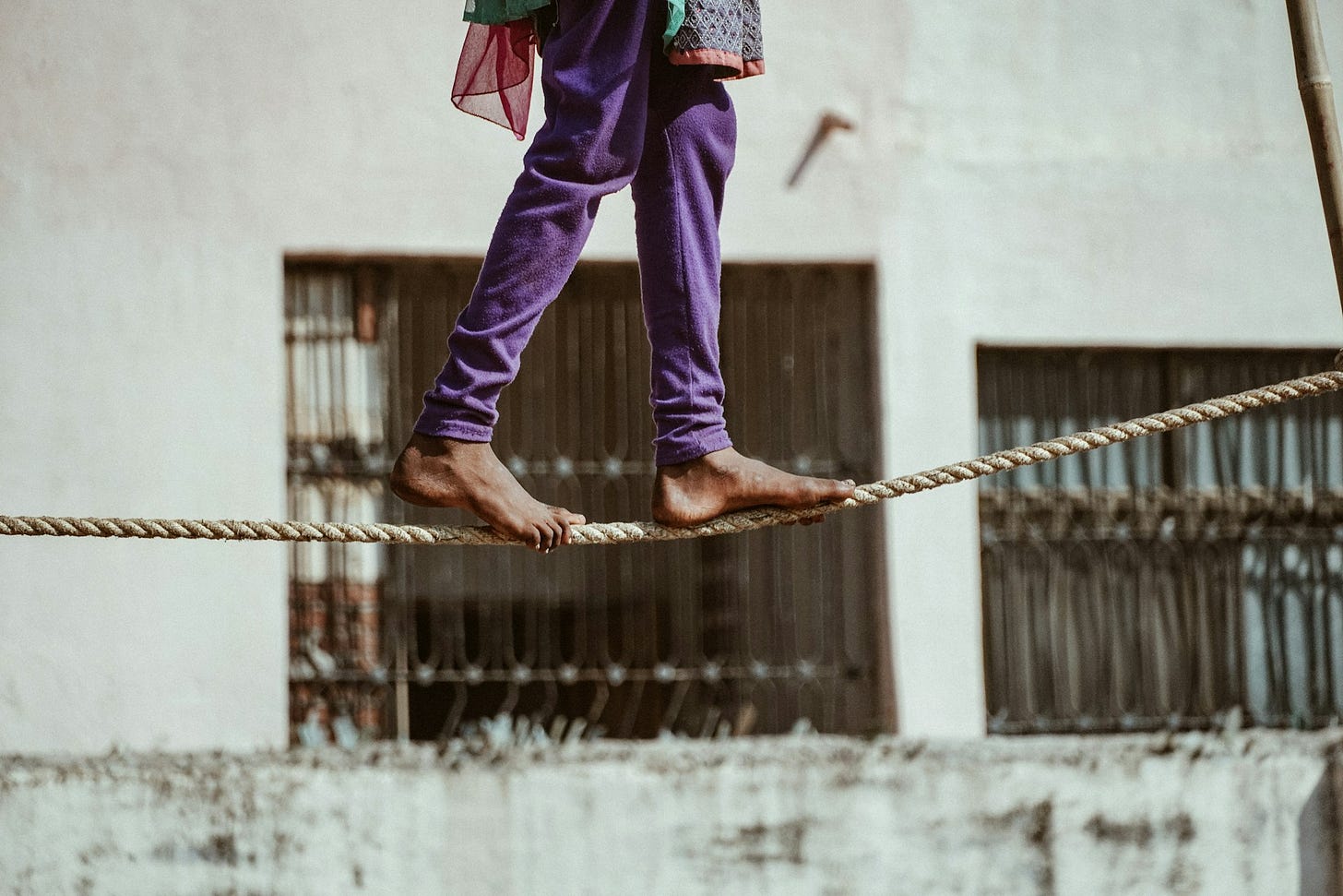 an indian woman in purple leggins walks on a rope suspended in the air