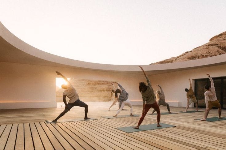 This may contain: a group of people are doing yoga on a wooden floor with mountains in the background
