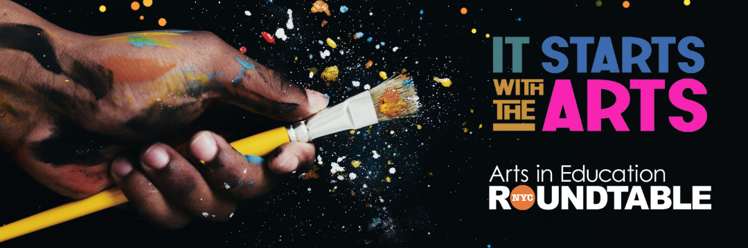 A Black hand is holding a paint brush, splattering different color pain everywhere. Text: It all starts with the arts from arts in education roundtable