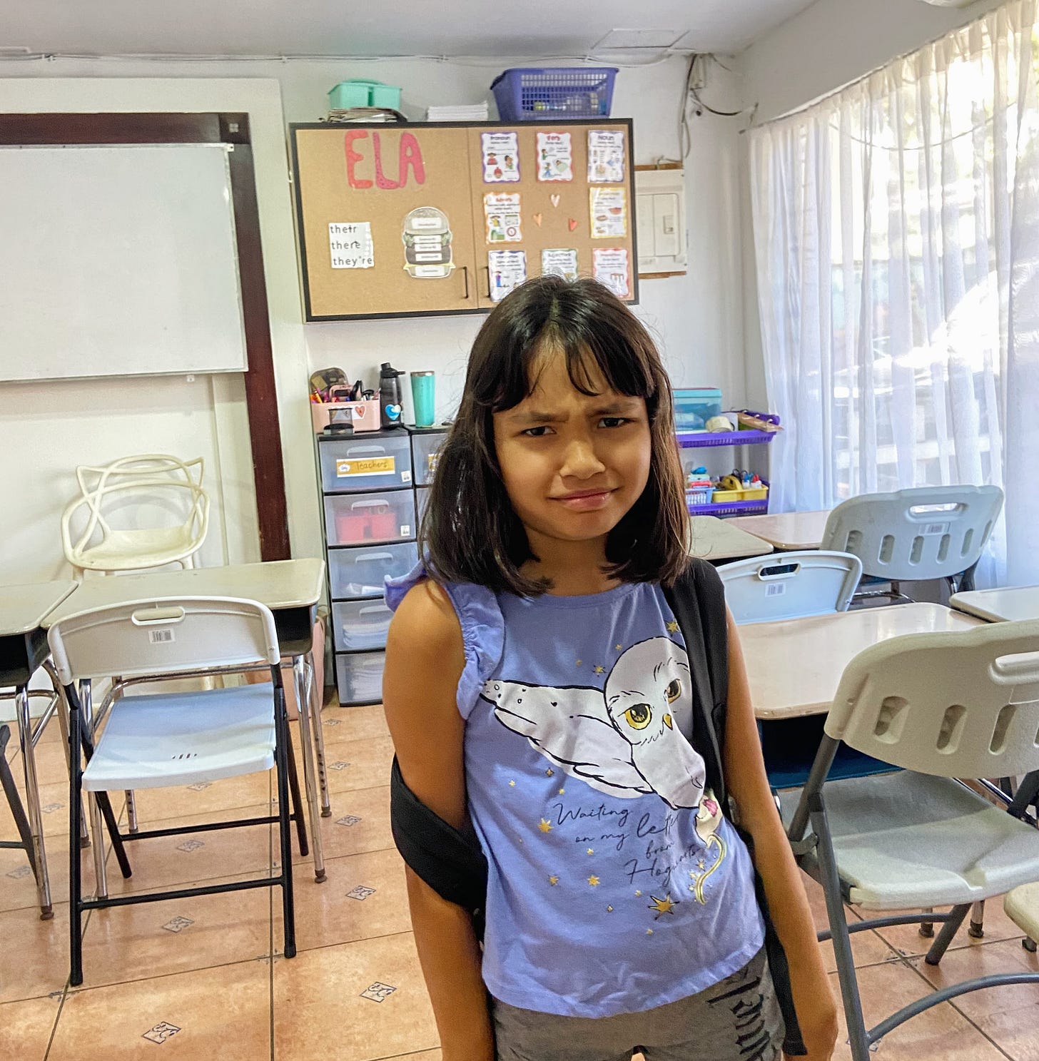 girl looking at camera and frowning inside a classroom