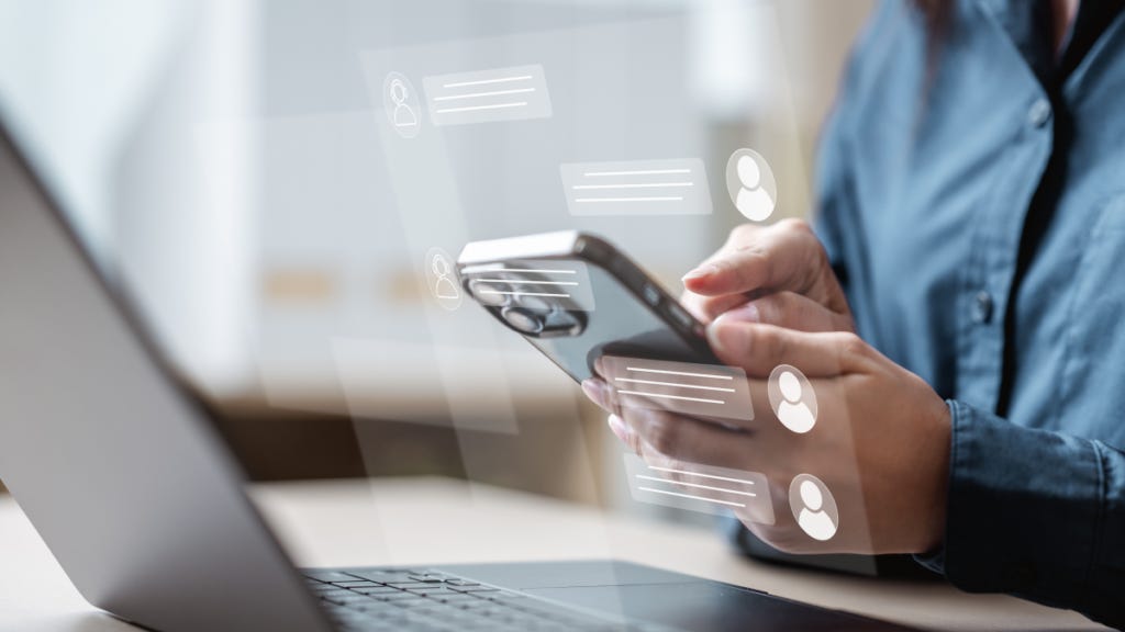 close up of hand using a phone in front of a laptop close up of hand using a phone in front of a laptop