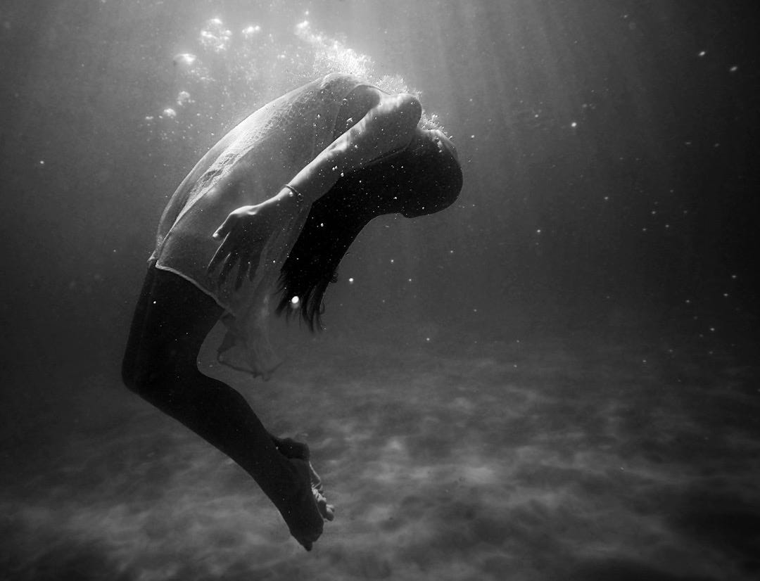 grayscale photo of woman drowning in water