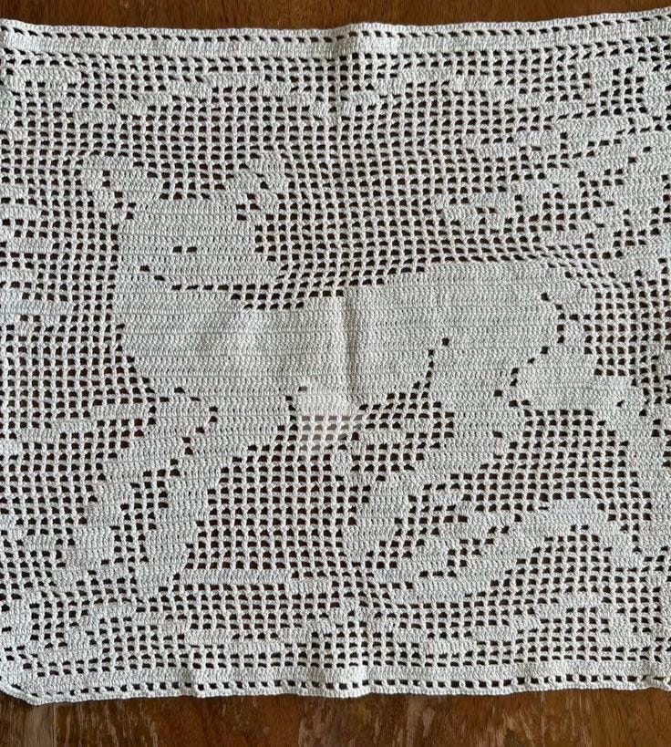 This may contain: a white crocheted doily on a wooden table
