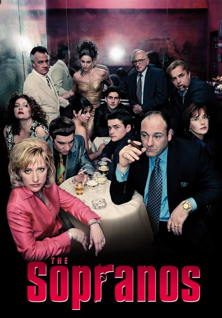 This may contain: a group of people sitting at a table in front of a poster for the soprano This may contain: a group of people sitting at a table in front of a poster for the soprano
