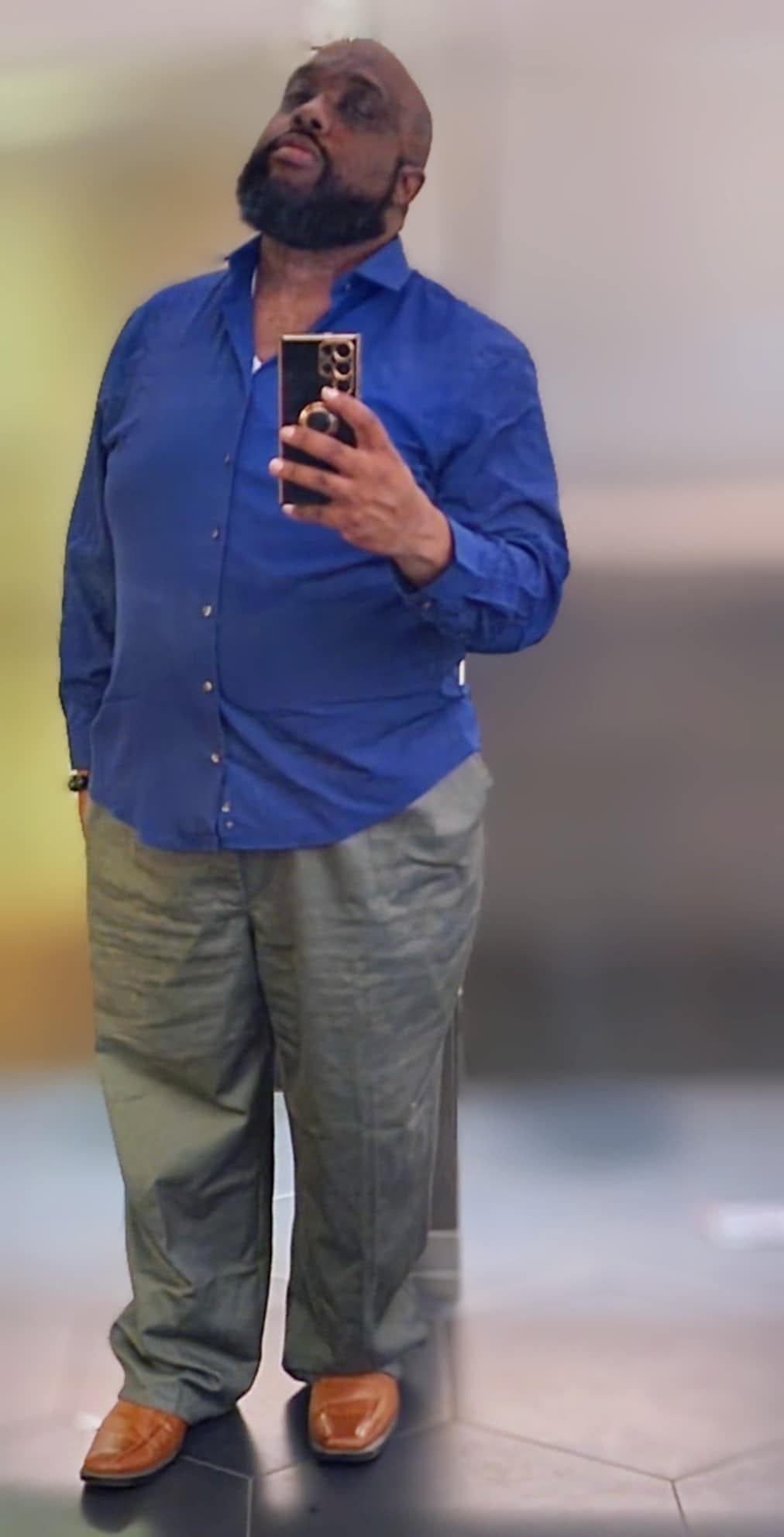 Photo of Matthew Elisha Williams. Taken on November 9th, 2024 inside the 21c Hotel in Kansas City, Missouri. matthew is wearing a Blue shirt, grey pants and light brown leather shoes.