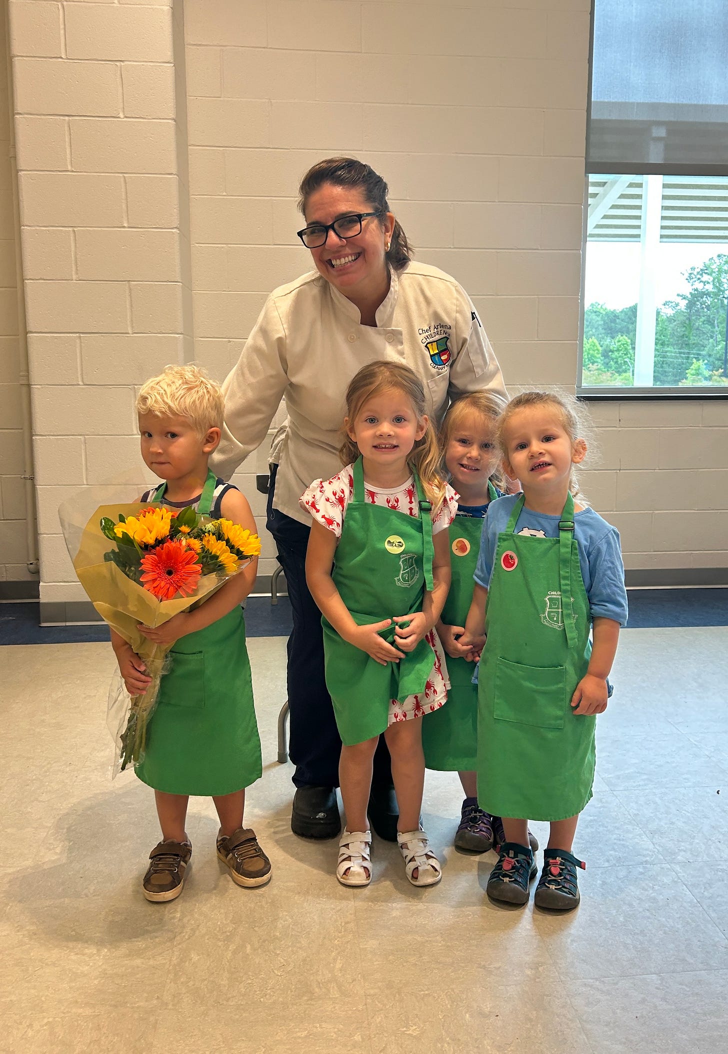 smiling chef posing for a picture with 4 young blonde children