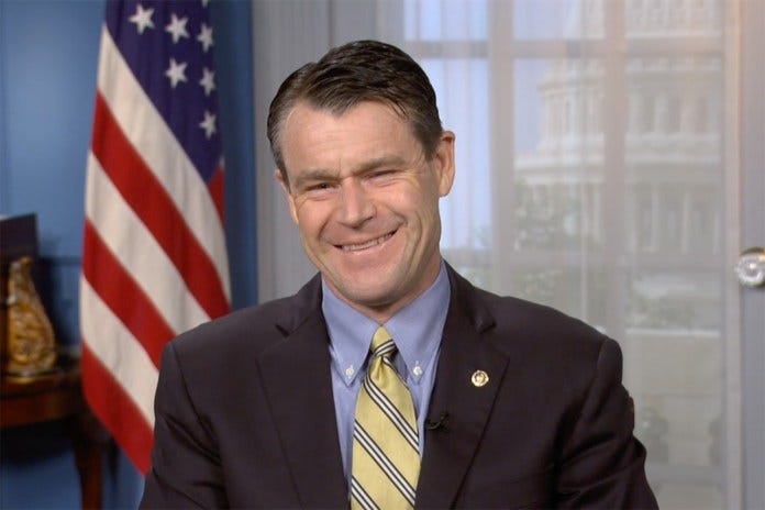 A person in a suit smiling

Description automatically generated