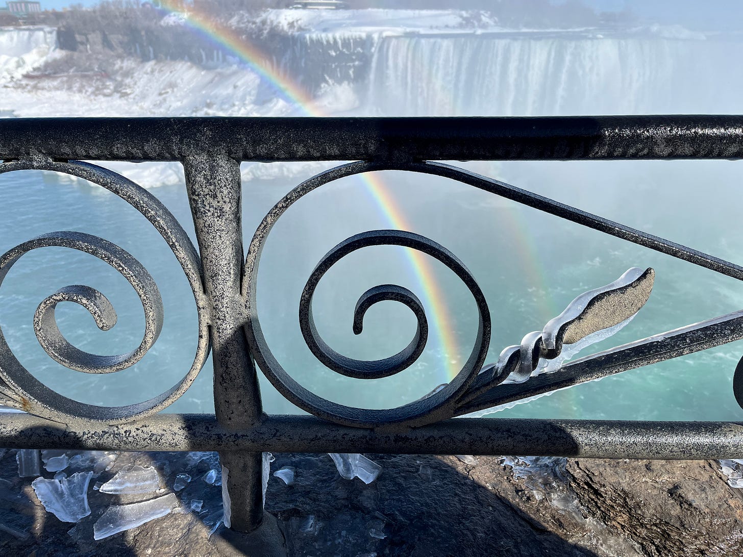 A cool ice formation on the iron railings at Niagara, backed by a rainbow and a view of Horseshoe Falls.