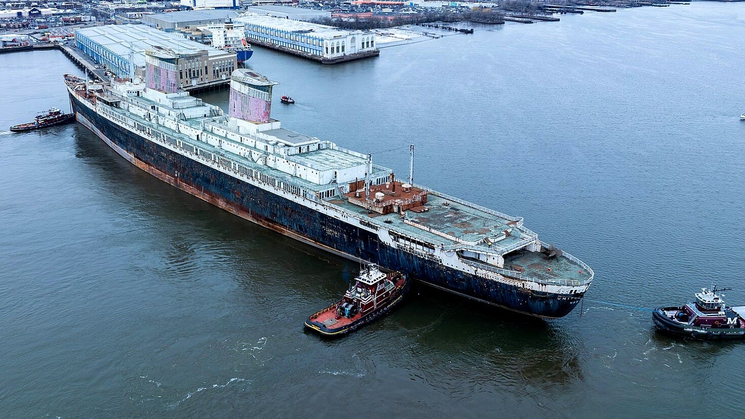 Tugboats guide the SS United States away from its Philadelphia pier in February 2025. Image: WSRower via Wikimedia Commons
