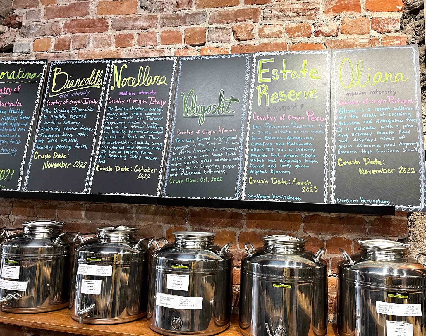 handwritten signs describing big steel containers of olive oil