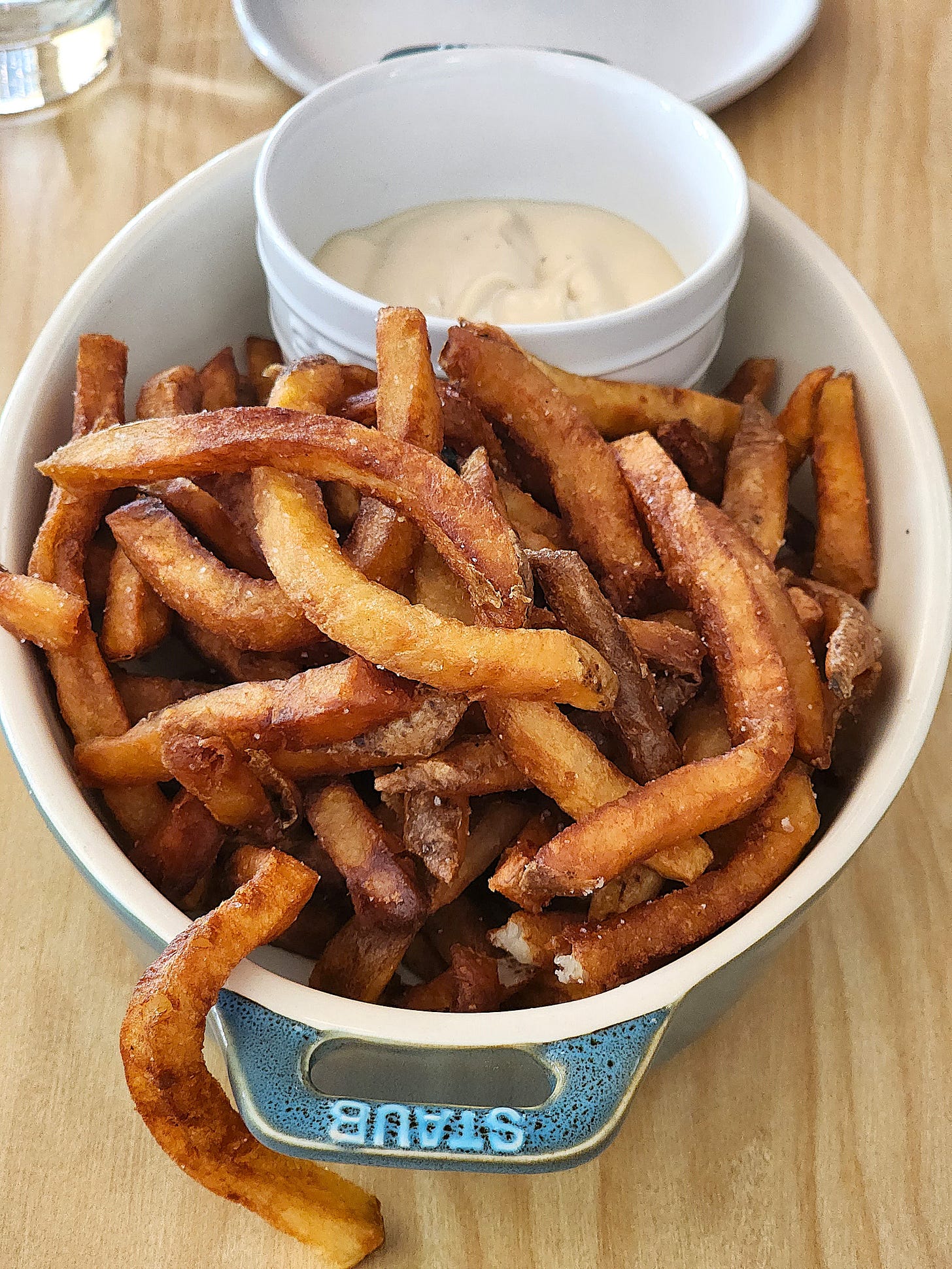A medium, overhead shot of a dish full of Cylde's Fine Diner's golden, crispy, kinda thick fries with a smaller bowl with a dipping sauce.