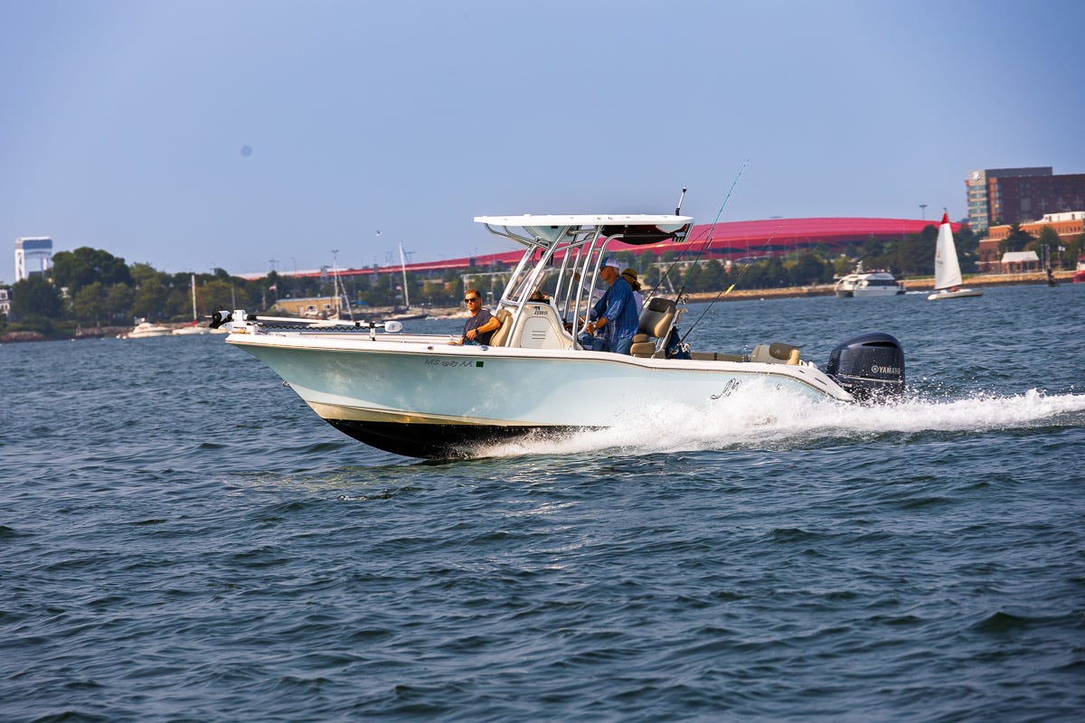 White center console fishing boat speeding across Boston Harbor with two people onboard