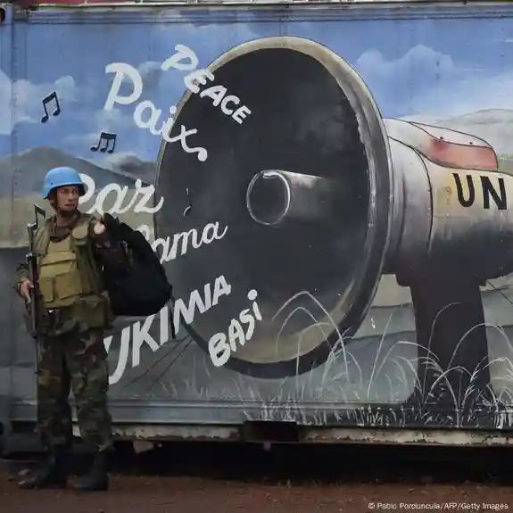 A UN peacekeeper stands infront of a mural. A UN peacekeeper stands infront of a mural.