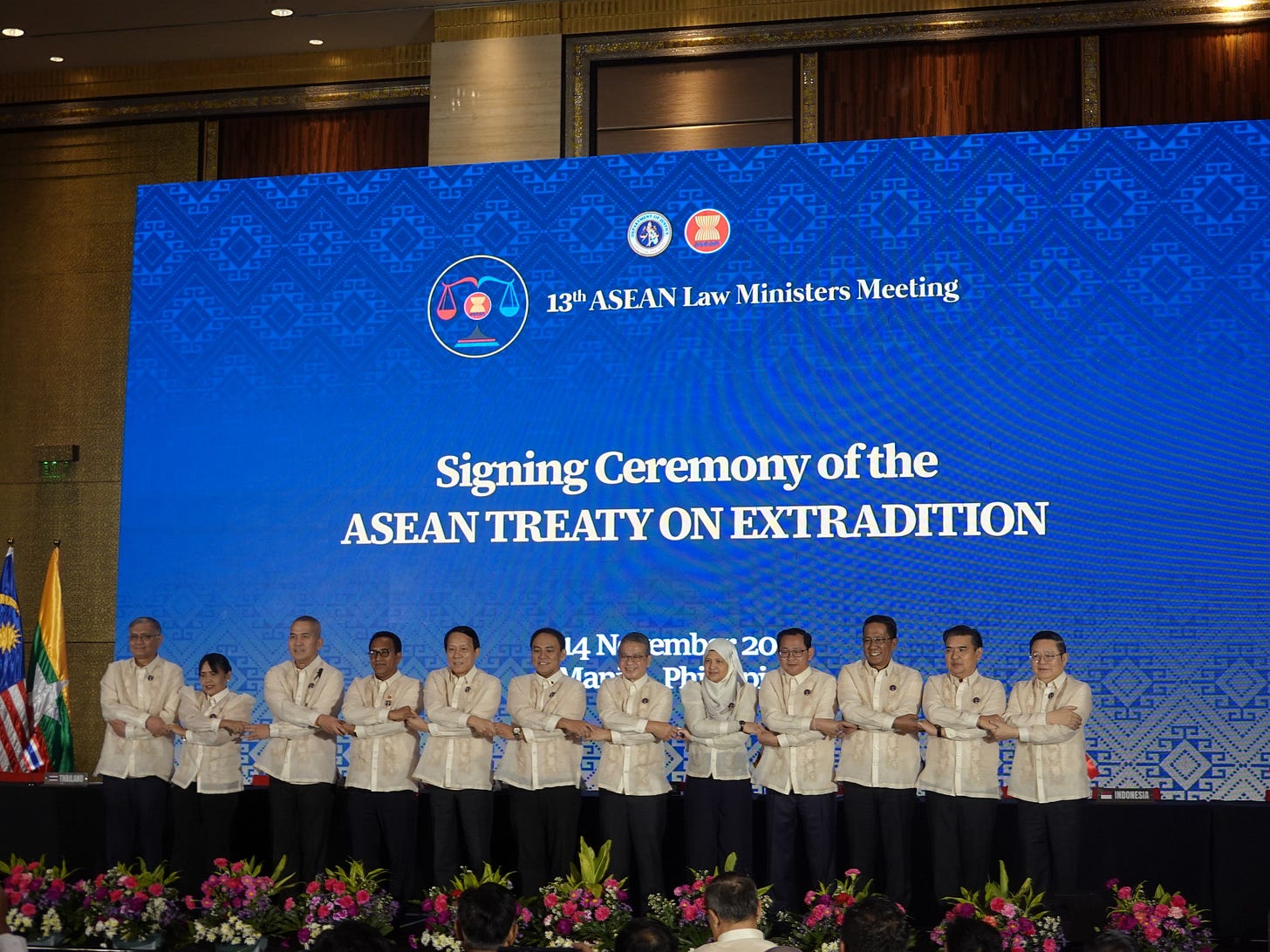 Delegates from all ten ASEAN member states stand in a row, crossing arms for the ASEAN handshake during the formal signing of the ASEAN Treaty on Extradition, representing solidarity and collective commitment.