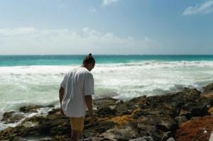 Photo by Dmitriy Piskarev - a man in white shirt walking on a rocky shore Photo by Dmitriy Piskarev - a man in white shirt walking on a rocky shore