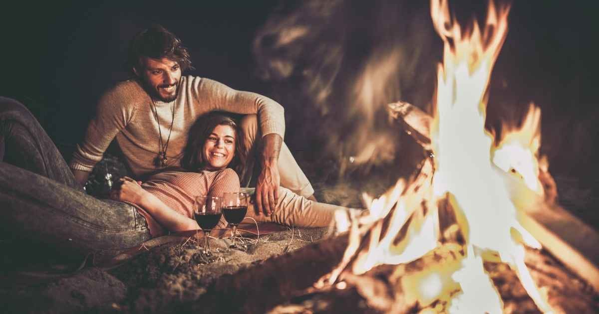 Happy relaxed couple enjoying in their date night by the campfire