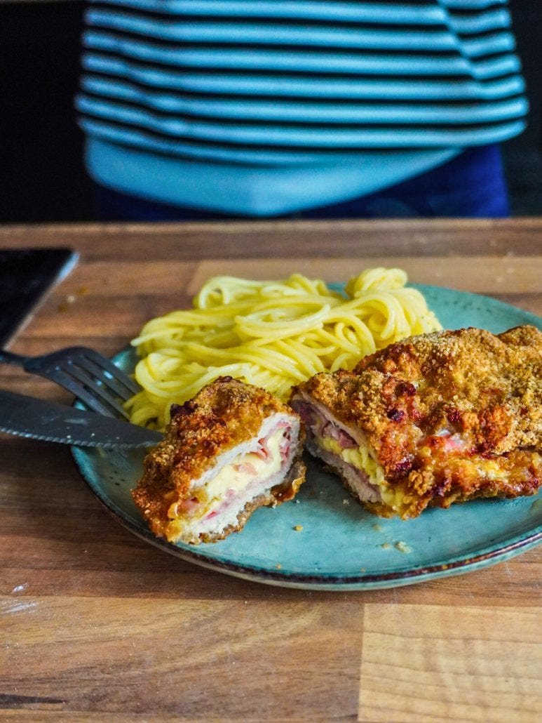 Cordon bleu fait maison, fromage et jambon, posé dans une assiette et coupé en deux.