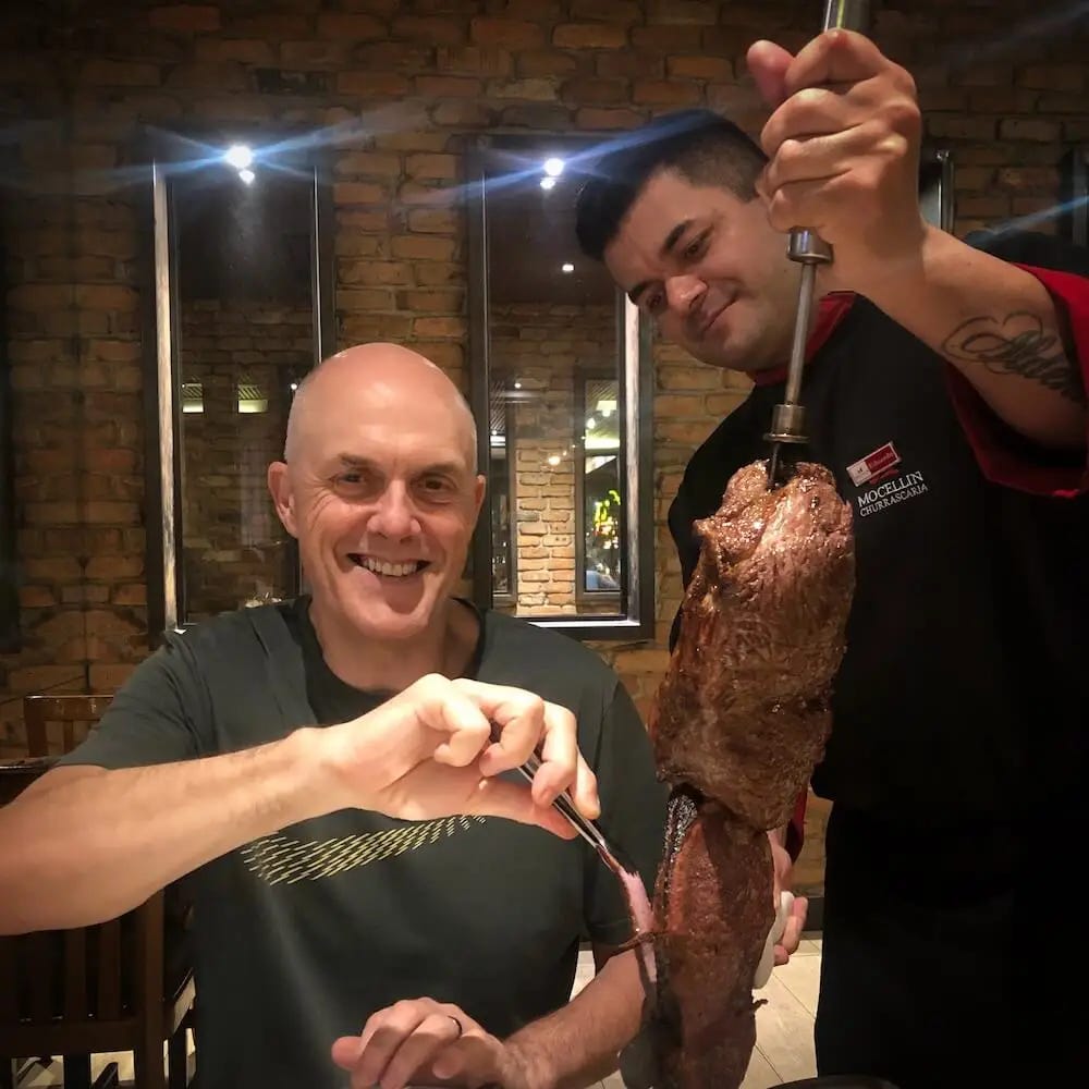 Ian watches on while a waiter carves meat from a skewer