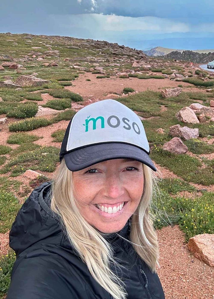 Author dressed professionally, fist under chin. Author selfie in the mountains. Both smiling.
