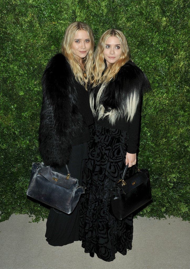 This may contain: two women standing next to each other in front of a green wall