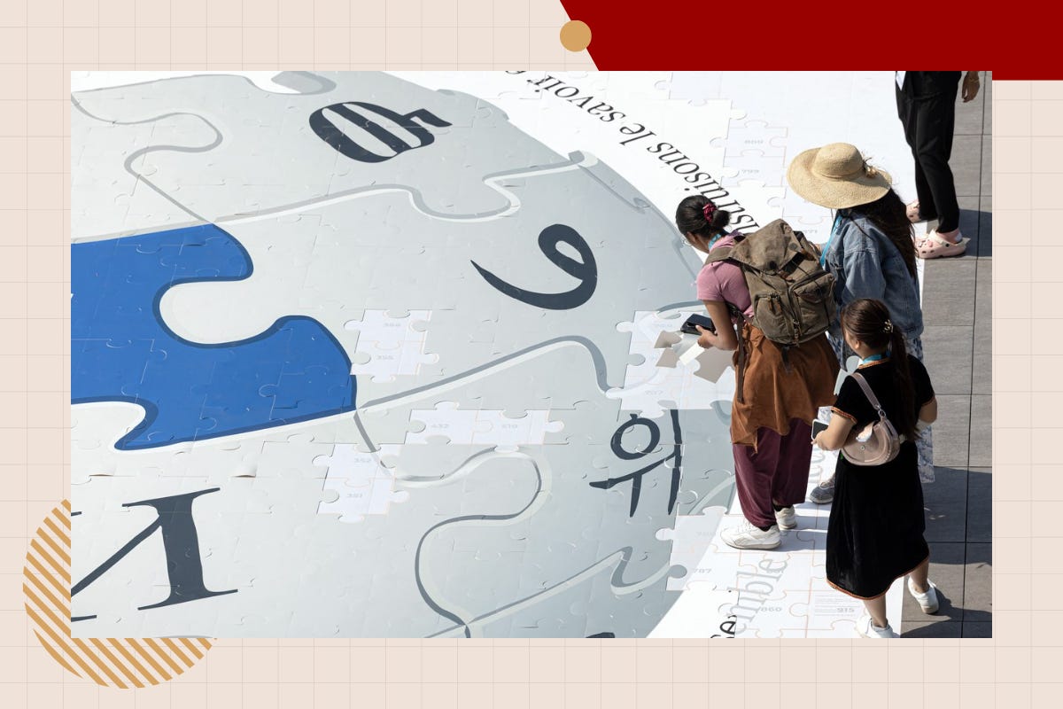 Overhead view of a giant Wikipedia puzzle globe laid flat on the ground, with three attendees, one in a straw hat, placing pieces along its edge. Overhead view of a giant Wikipedia puzzle globe laid flat on the ground, with three attendees, one in a straw hat, placing pieces along its edge.