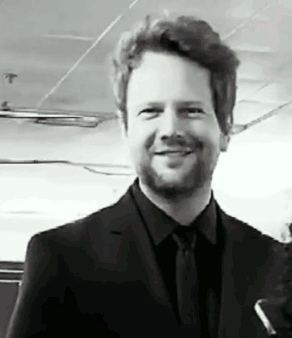 a man with a beard is wearing a suit and tie and smiling .