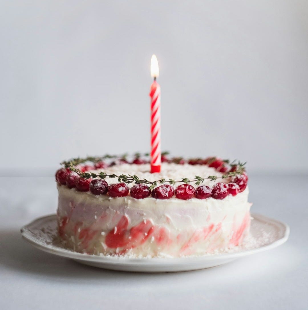 white and pink covered cake with lightened candle