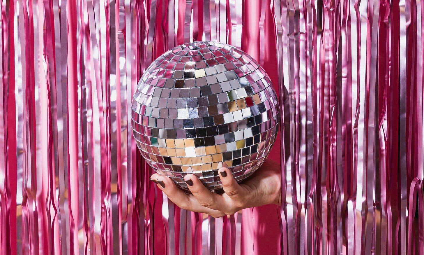 Hand reaching through streamers holding a disco ball