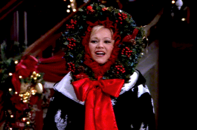 This may contain: a woman wearing a wreath on top of her head in front of a christmas tree