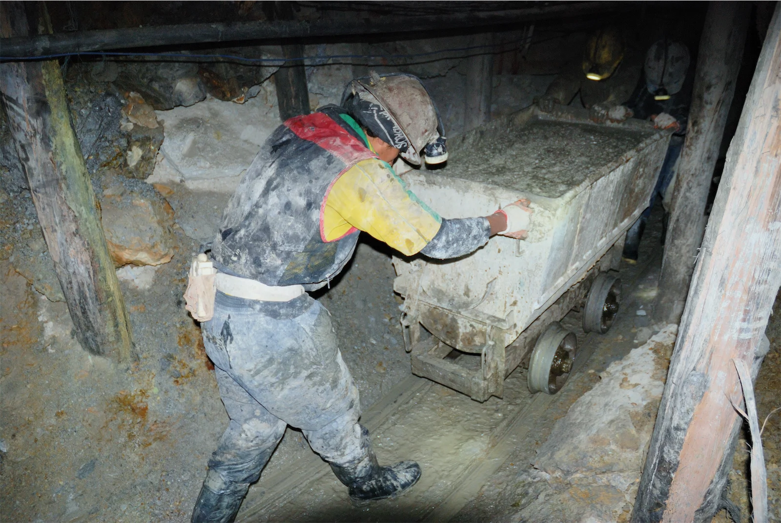 miners in a tin mine in potosi pushing a cart with tin sediments