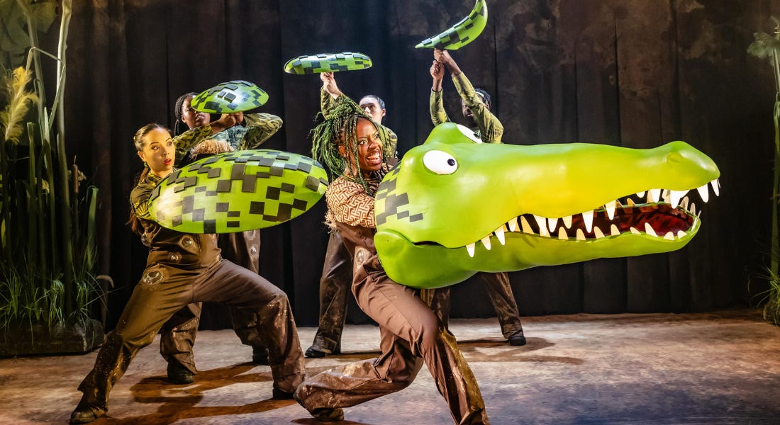 A woman - Chelsea Da Silva - with a crocodile puppet head, with actors behind her with green scales