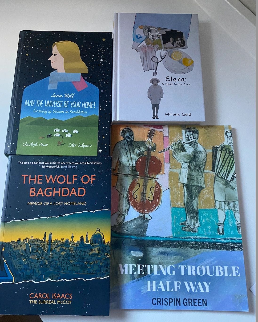 Signed copies of some of the graphic memoirs I featured in 2025, after meeting and interviewing the creators in London:  From left-to-right, top-and-bottom row layout:  Top row:  May the Universe Be Your Home! — Lena Wolf  Elena: A Hand-Made Life — Miriam Gold  Bottom row:  The Wolf of Baghdad — Carol Isaacs  Meeting Trouble Halfway — Crispin Green