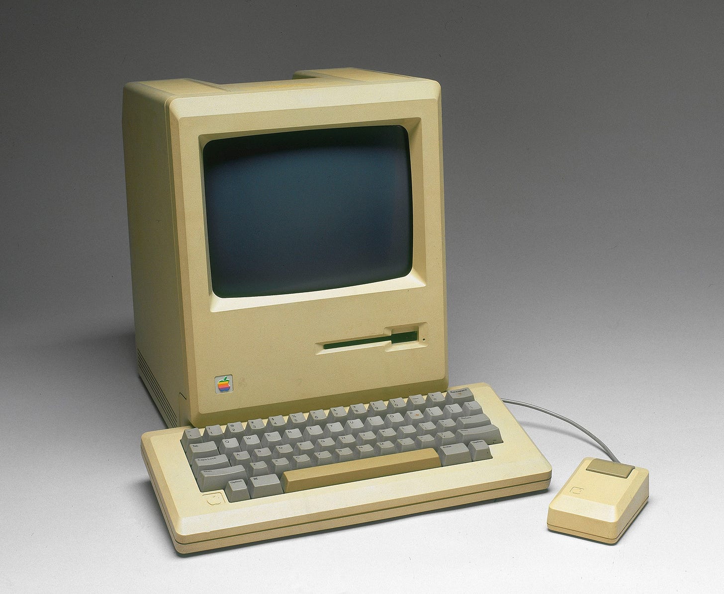 Vintage Apple computer with a keyboard and mouse on a grey background Vintage Apple computer with a keyboard and mouse on a grey background