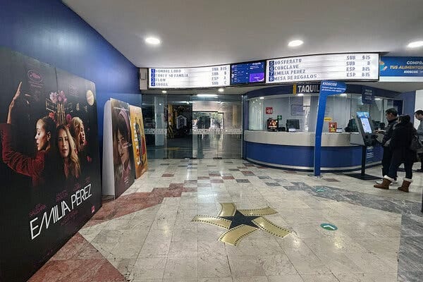El interior de un cine con un afiche de la película Emilia Pérez a la izquierda.
