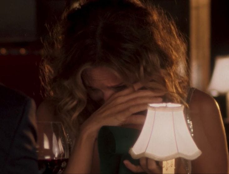 This may contain: a woman covering her face next to a lamp