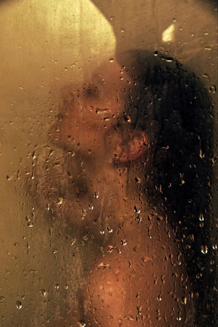 This may contain: a woman is seen through the rain covered window