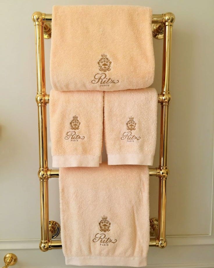 This may contain: three towels are hanging on a gold towel rack
