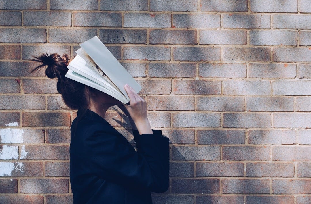 woman covering her face with white book woman covering her face with white book