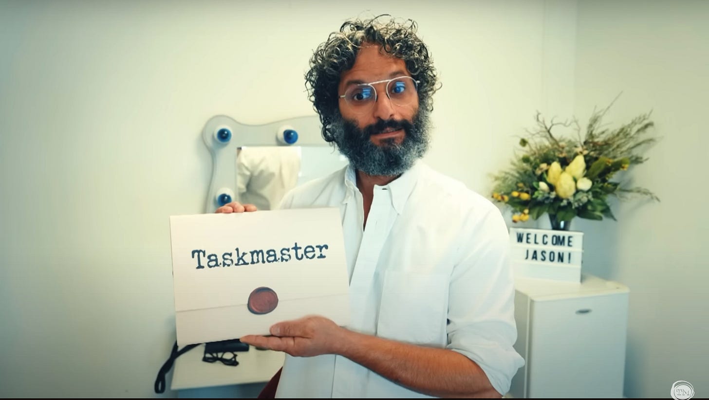 Jason Mantzoukas holds the Taskmaster pop-up book in his dressing room.